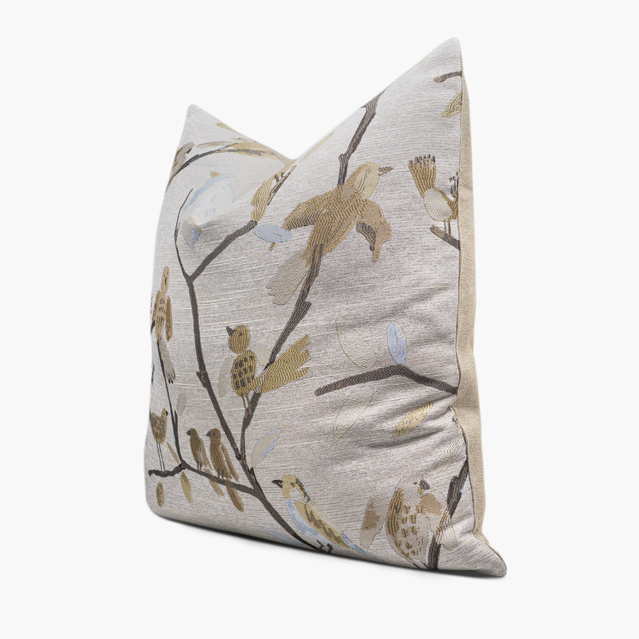 Side view of a decorative throw pillow with a pattern of gold and blue birds sitting on branches