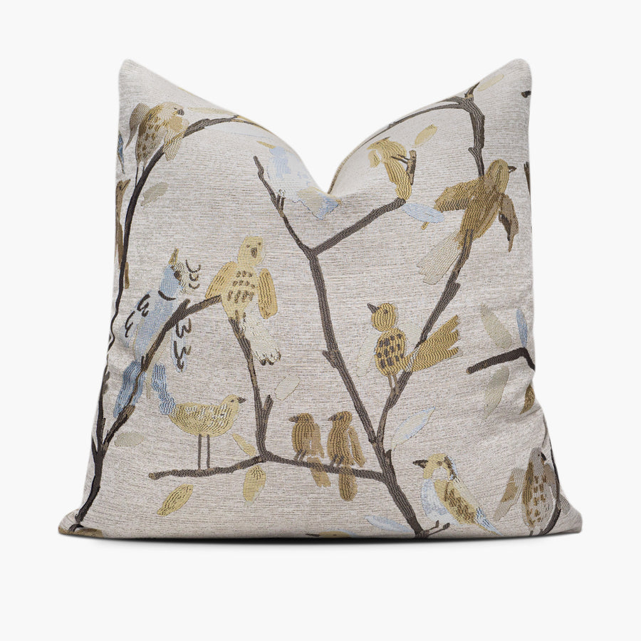 Decorative throw pillow with a pattern of gold and blue birds sitting on branches