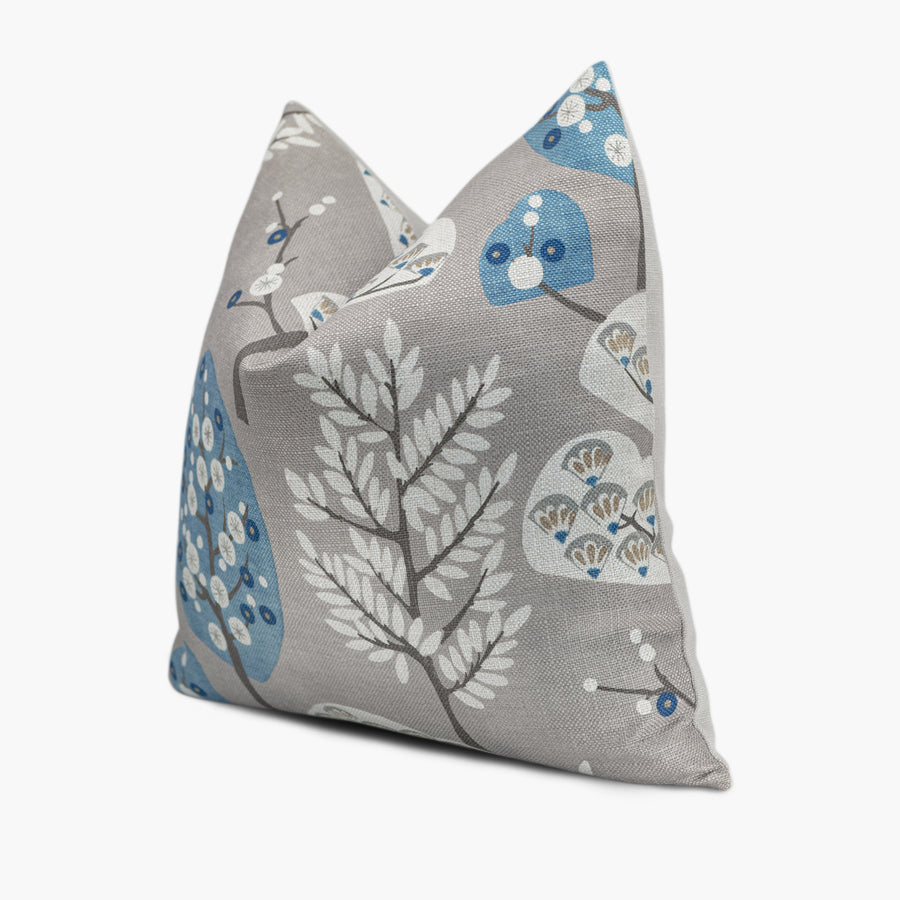 Quarter view of a mid-century modern throw pillow with a blue and gray tree motif