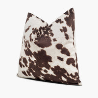 Side view of brown and white cowhide throw pillow