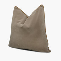 Side view of brown velvet throw pillow with gold piping