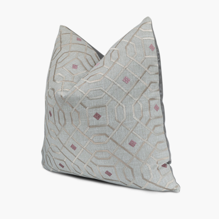 Quarter view of an embroidered throw pillow with a silver mosaic motif with purple diamonds