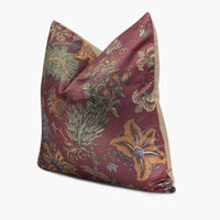 Side view of burgundy red throw pillow with a floral and exotic bird motif