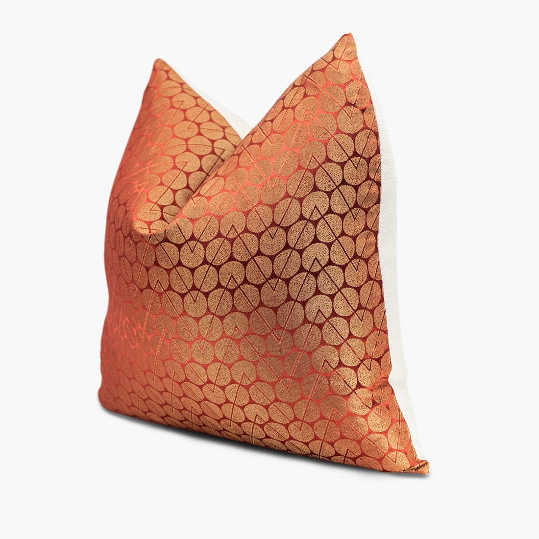 Quarter view of a geometric throw pillow with a circle and zigzag motif in iridescent gold and orange