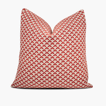 A ruby red and gold throw pillow with a geometric pattern sits against a white background.