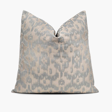 A throw pillow with a silvery ikat motif sits against a white background.