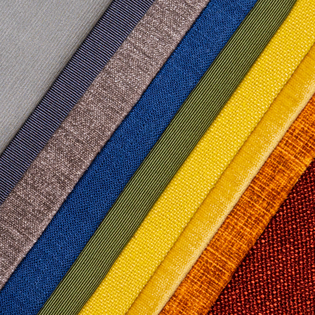 Several fabrics are neatly arranged to create a rainbow of colors