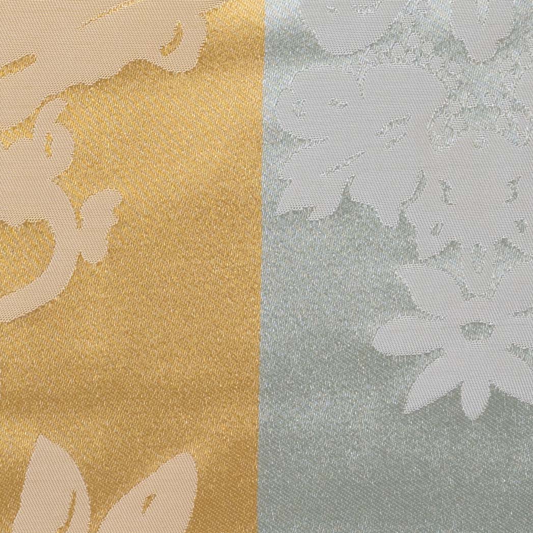 A close-up of a silk-blend fabric in gold and green with a damask motif.